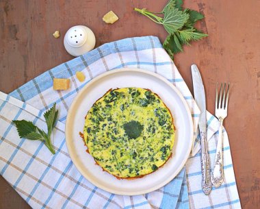 Kahvaltı, beyaz kil tabakta ısırgan otlu omlet. Sağlıklı yiyecekler. Yabani otlardan alınan yiyecekler. Üst görünüm, alanı kopyala.