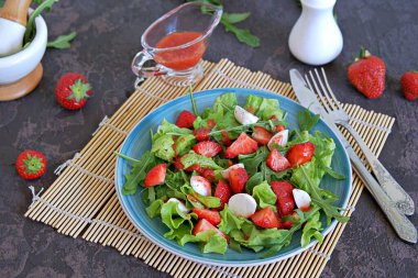 Çilekli salata, roka ve koyu kahverengi arka plan betonunda mozzarella peyniri. Sağlıklı yemek..