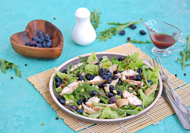 Arugula salatası, marul, ızgara tavuk ve turkuaz arka planda kahverengi bir tabakta hanımeli. Sağlıklı yiyecekler, diyet. Seçici odak