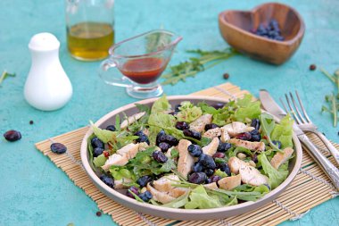 Arugula salatası, marul, ızgara tavuk ve turkuaz arka planda kahverengi bir tabakta hanımeli. Sağlıklı yiyecekler, diyet. Seçici odak