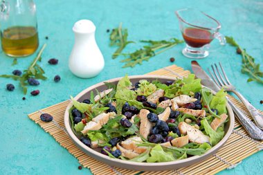 Arugula salatası, marul, ızgara tavuk ve turkuaz arka planda kahverengi bir tabakta hanımeli. Sağlıklı yiyecekler, diyet. Seçici odak