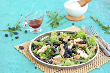 Arugula salatası, marul, ızgara tavuk ve turkuaz arka planda kahverengi bir tabakta hanımeli. Sağlıklı yiyecekler, diyet. Seçici odak