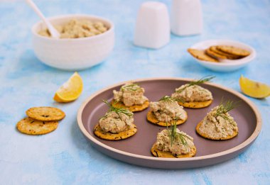 Aperatif, balık ezmesi, haşlanmış yumurta ve soğan kahverengi tabakta mavi beton arka planda. Balık tarifleri.