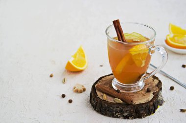 Baharatlı elma şarabı. Alkolik ya da alkolsüz taze filtresiz elma suyundan yapılmış baharatlar, elma dilimleri ve portakallı hafif beton bir arka planda cam bardak. Boşluğu kopyala.