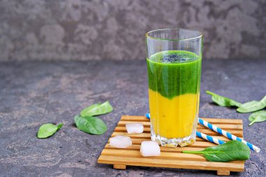 Sağlıklı bir içecek, taze ıspanaklı iki katmanlı smoothie ve koyu beton arka planda uzun bir bardakta olgun mango. Arınma ve kilo kaybı için içecekler. Kopyalama alanı.