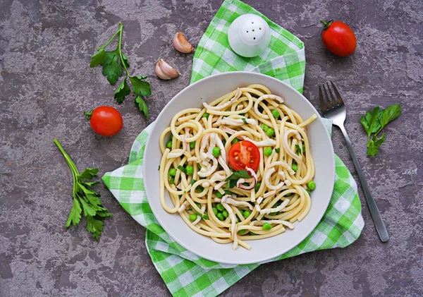 黒灰色のコンクリートの背景に灰色のボウルにイカと緑のエンドウ豆とブキャティーニパスタ イタリア料理 — ストック写真