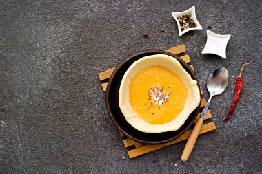 Kahverengi tepside, gri beton arka planda yenilebilir ekmek tabağında balkabağı püresi çorbası. Balkabağı tarifleri. Şükran Günü.