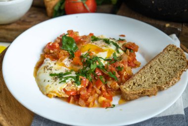 İsrail usulü omlet, shakshuka ve siyah ekmek ile beyaz tabak yakın çekim