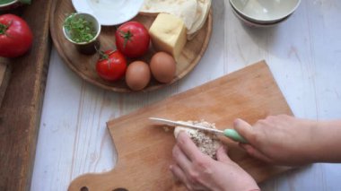 Yemek pişirmek için ızgara tavuk göğsü kesen biri.