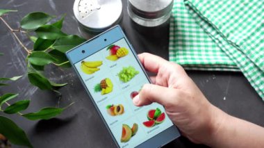 Çevrimiçi meyve alışverişi için akıllı telefon ekranını kaydıran kişi.
