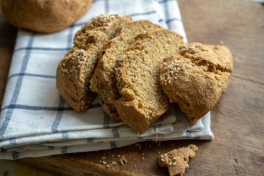 Ev yapımı siyah ekmek, dilimlenmiş diyet hamur ekmeği tam tahıllı un ve tahtadan kesme tahtasında susam.