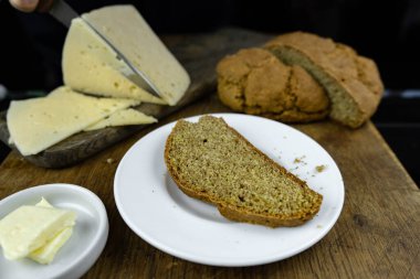 Tereyağlı, sütlü ve peynirli ev yapımı siyah ekmek. Siyah zemin üzerinde tahıllı un bulunan diyet mayasız çörek. Köy kahvaltısı eski ahşap masada.