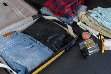 Seyahat için toplanıyorum. Sarı plastik çantaya küçük şişelerle giysi ve sıvılar koymak.