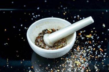 Özel beyaz bir kasede ezilen baharat ve tuz çeşitleri ve siyah arka planda ağırlık var.