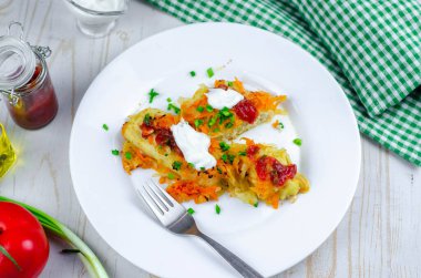 Havuçlu ev yapımı lahana ruloları, beyaz tabakta kırmızı domates sosu ve krema.