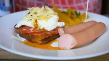Kızarmış ekmek, haşlanmış yumurta ve peynir, sosis ve sebze salatası.