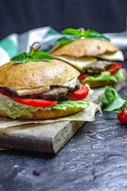 Biftek, domates, peynir ve fesleğenli sağlıklı ev yapımı hamburger.