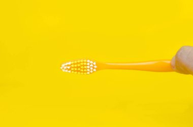 Sarı arka planda basit turuncu diş fırçası, minimum fotoğraf