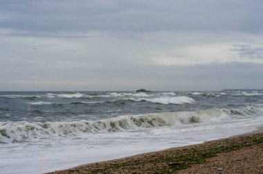 Kum sahilinde köpüklü okyanus dalgaları.