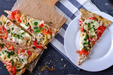 Tavuklu, domatesli, biberli, ahşap kesme tahtasındaki mozzarella soslu sağlıklı pizza dilimleri. Beyaz tabakta bir dilim pizza. Karanlık arka planda düzgün beslenme. en üstteki görünüm