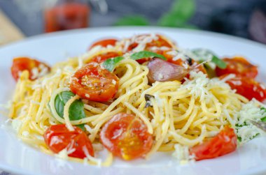 Sarımsaklı, kirazlı, domatesli ve fesleğenli taze makarna. Lezzetli makarna tabağı. Spagetti. İtalyan yemeği. İtalya. Roma. Güzel yemek. Sağlıklı yiyecekler. Vejetaryen. Sağlıklı yemek.