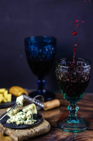 Vintage wine glasses and bottle of red wine on a wooden table. Blue cheese cut on the old cutting board