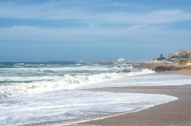 Kum sahilinde köpüklü okyanus dalgaları.