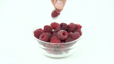 Taze olgun bir ahududu beyaz arka planda cam şeffaf bir kaseye koy.