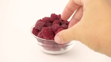 Taze olgun bir ahududu al ve beyaz arka planda cam şeffaf bir kasede koy.