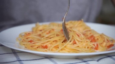 Beyaz insan ev yapımı makarnayı domates ve peynirli çatalla çeviriyor.