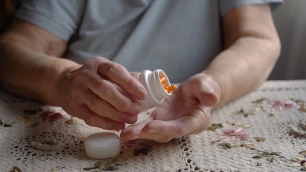 老婦人のスローモーションショット白い枕からオレンジの丸薬を取ります シニア女性の手 引退した人々の健康管理 — ストック動画