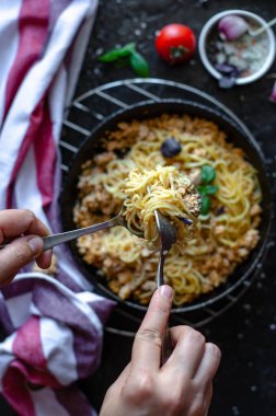 Masadaki tavada domates, sarımsak ve fesleğenle servis edilen bolonez soslu spagetti. Kızartma tavasında İtalyan makarnası