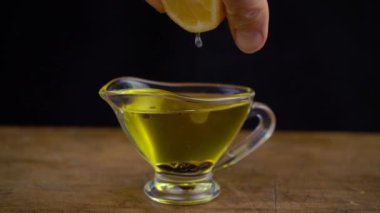 Siyah arka planda zeytinyağı, limon ve balzamik sirkeden sos yaparken yavaş çekim.