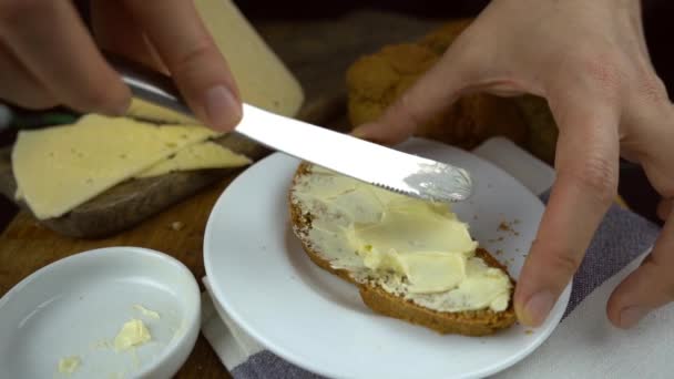 在自制的农村黑面包上涂黄油的慢镜头 无酵母面包 全麦面粉和奶酪 黑色背景 乡村式早餐 放在旧木桌上 — 图库视频影像