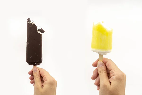 set of white vanilla ice cream on stick with chocolate glaze in a hand, summer refresh bite cold ice cream