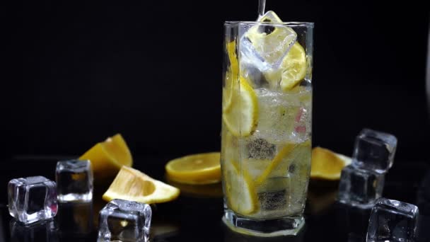 輝く水やレモンと氷のカクテル 黒を背景にガラスの白いソーダ さわやかな冷たい飲み物 — ストック動画