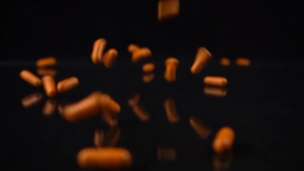 橙色药丸的慢镜头落在镜像的黑桌上 弹跳了起来 药物成瘾概念 — 图库视频影像