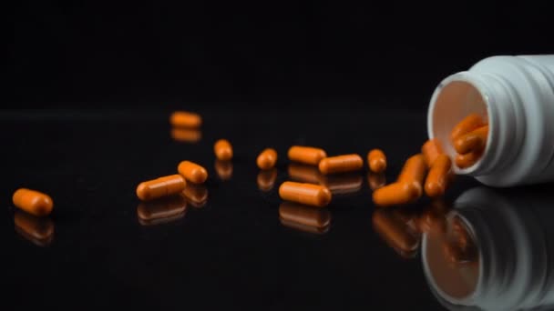 Zpomalený Záběr Oranžových Pilulek Padajících Bílé Láhve Zrcadlový Černý Stůl — Stock video