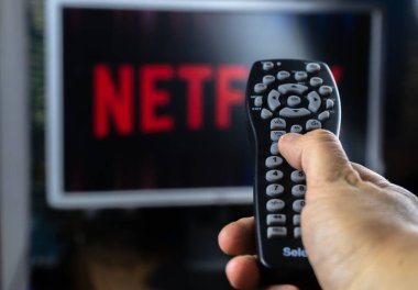 Netflix logolu televizyon ekranının önündeki uzaktan kumanda