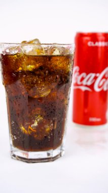 Buzlu bir bardak soğuk, ferahlatıcı kola, metal bir kutu coca-cola klasiği, 4k dikey..