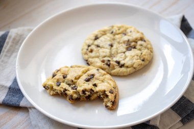 Tabağında fındık olan taze, klasik çikolatalı kurabiyeler.
