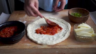 Evde pizza yapmak, kadın pizza hamuruna domates sosu sürmek, Napoli pizzası margherita 
