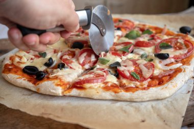 Ev yapımı pizzayı erimiş peynirle ve domatesle dilimleyin.