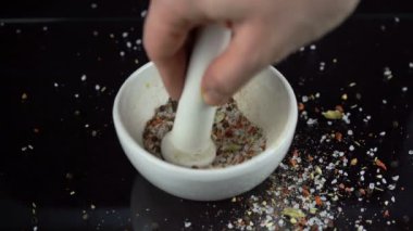 Özel beyaz bir kasede ezilen baharat ve tuz çeşitleri ve siyah arka planda ağırlık var.