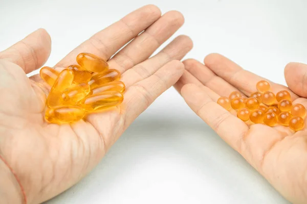 omega 3 big gel capsules and fish oil small capsules in a hand, healthcare, vitamins