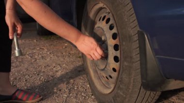 Kadın, arabanın lastiğini değiştirdikten sonra manuel anahtarla sürgüyü sıkılaştırır.