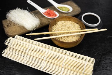 Japon mutfak arka planı bambu hasırı, yemek çubuğu, soya sosu, turşu ve esmer pirinç.