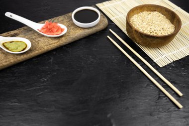 Japon mutfak arka planı bambu hasırı, yemek çubuğu, soya sosu, turşu ve esmer pirinç.