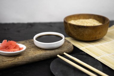 Japon mutfak arka planı bambu hasırı, yemek çubuğu, soya sosu, turşu ve esmer pirinç.
