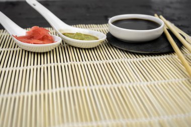 Japon mutfak arka planında bambu hasırı, yemek çubuğu, siyah arka planda soya sosu.